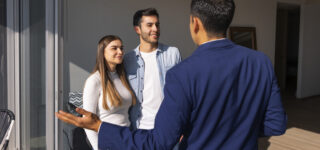 Agent immobilier faisant visiter un appartement à un couple d’acheteurs à la rentrée.