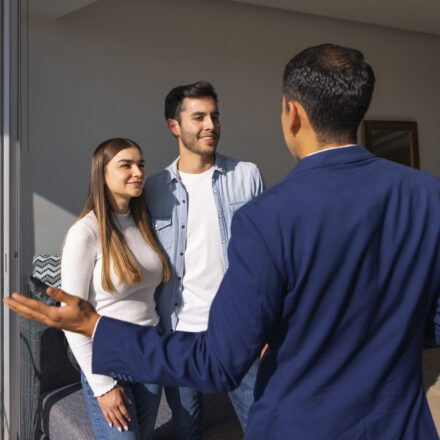 Agent immobilier faisant visiter un appartement à un couple d’acheteurs à la rentrée.