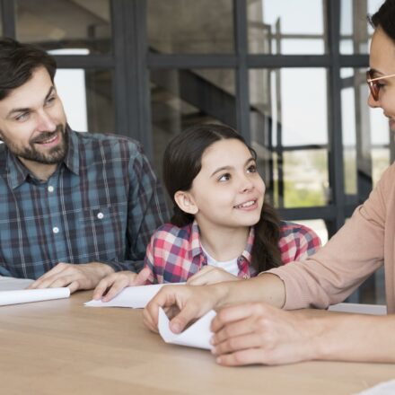 Famille préparant la rentrée scolaire tout en signant un contrat d’achat immobilier.