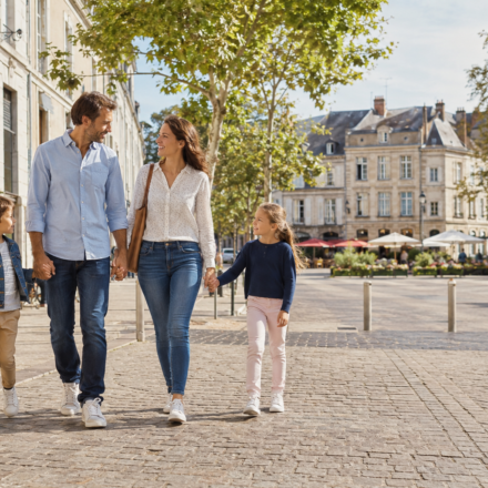 Achat Immobilier : les petites préfectures deviennent-elles une alternative immobilière crédible aux grandes métropoles ? Famille dans le centre-ville animé d’une petite préfecture française