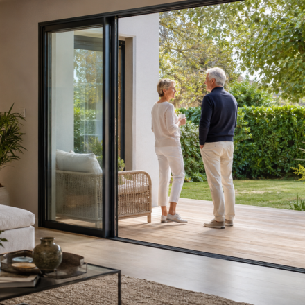 Immobilier et les rez-de-chaussée : retrouvent-ils de la valeur avec le vieillissement de la population ? Couple de seniors dans un appartement accessible en rez-de-chaussée ouvert sur un jardin