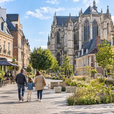Immobilier à Beauvais : vivre à proximité de l’Île-de-France sans ses prix Famille se promenant dans le centre de Beauvais devant la cathédrale Saint-Pierre