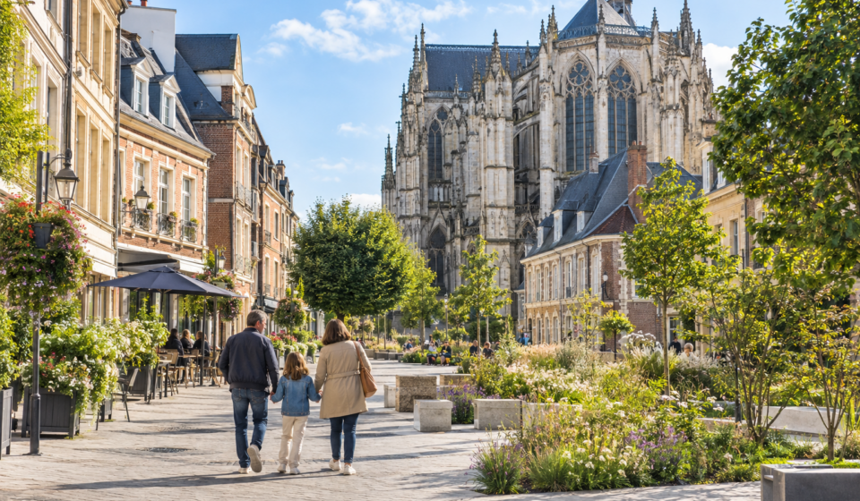 Immobilier à Beauvais : vivre à proximité de l’Île-de-France sans ses prix Famille se promenant dans le centre de Beauvais devant la cathédrale Saint-Pierre