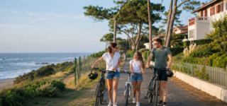 Une famille se promène à vélo près de l’océan et des quartiers résidentiels d’Anglet