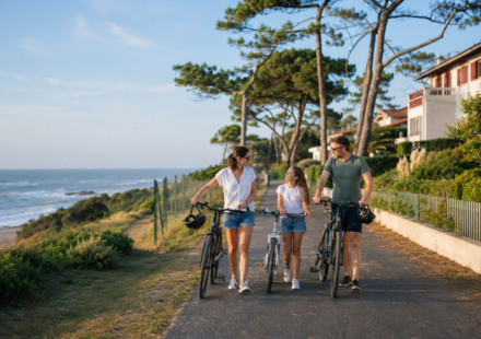 Vivre à Anglet : immobilier, océan et qualité de vie au cœur du Pays basque Une famille se promène à vélo près de l’océan et des quartiers résidentiels d’Anglet