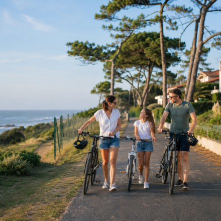 Une famille se promène à vélo près de l’océan et des quartiers résidentiels d’Anglet
