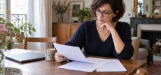 Une acquéreuse relit les conditions de son offre d’achat à son domicile.
